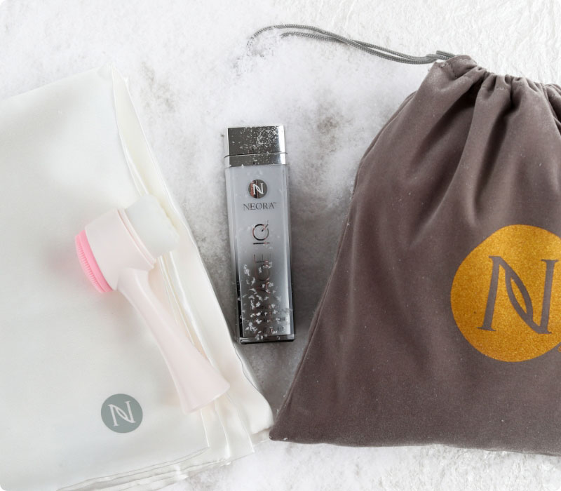 Neora’s hottest holiday must-have, the Beauty Sleep Set, which includes Age IQ Night Cream, Satin Pillowcase 1 Queen/Standard size pillowcase, FREE Dual-Action Facial Cleansing Brush and FREE Gift Bag laying on a bed of snow.